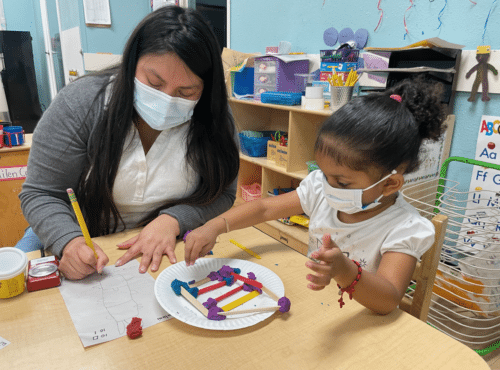 Woman assisting a child with art creation.