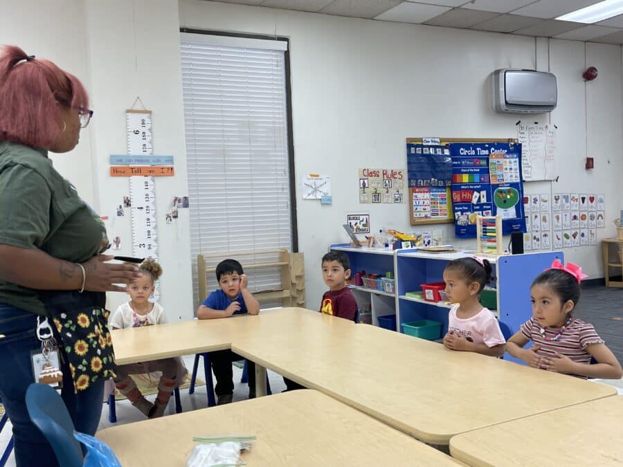 Five children listening to an adult woman.